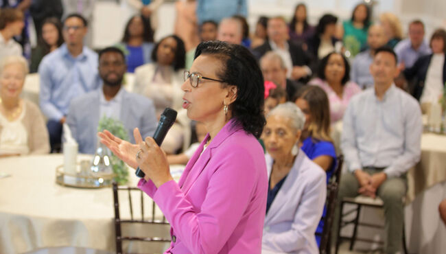 A celebrant speaks to a crowded room during a celebration of life